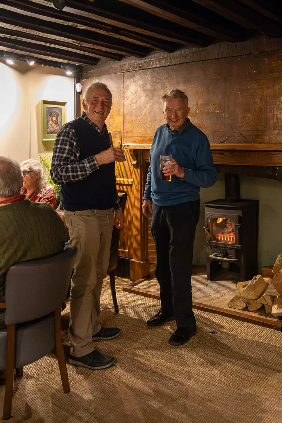 Friends enjoying a pint by the fireplace at the Rose & Crown, Ashdon