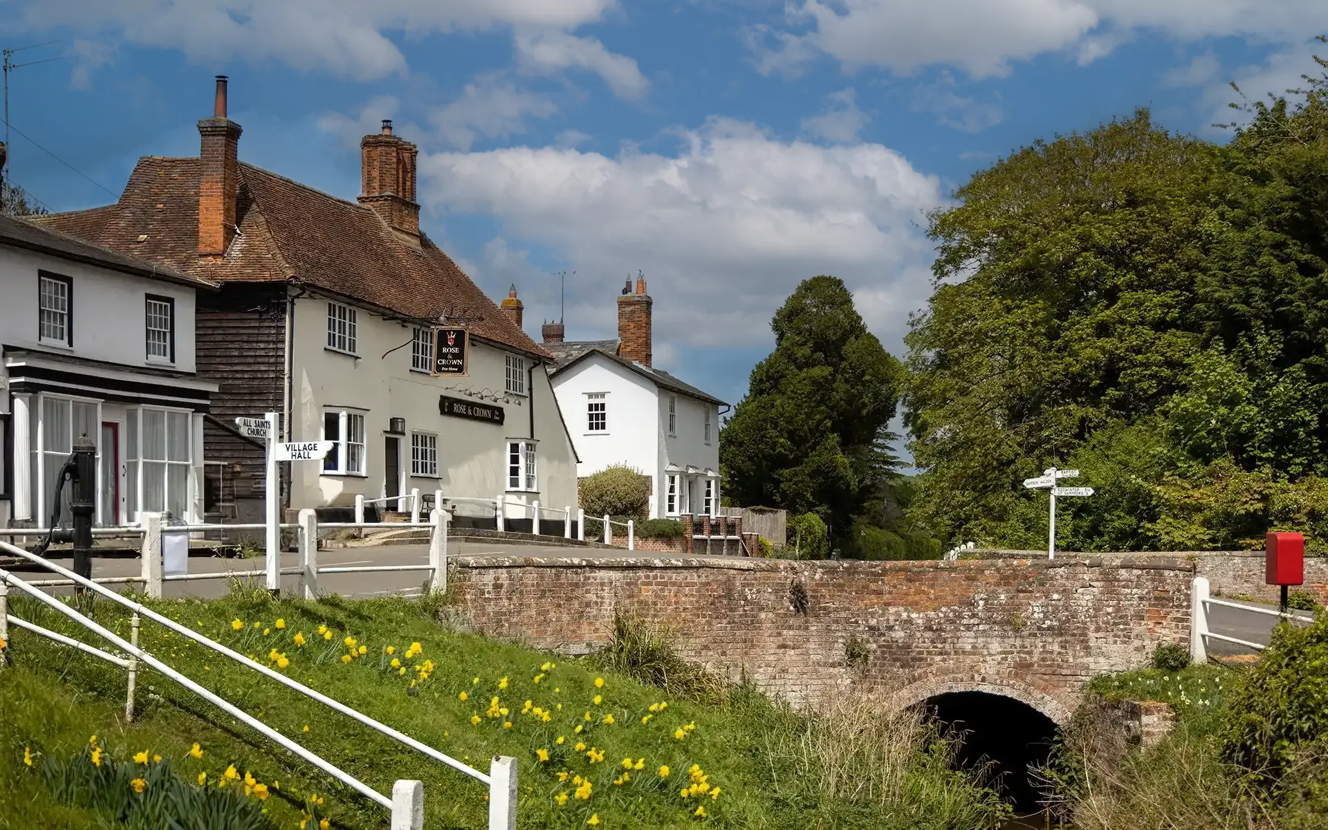 The Rose & Crown, Ashdon, beside the village bridge with spring daffodils on the bank