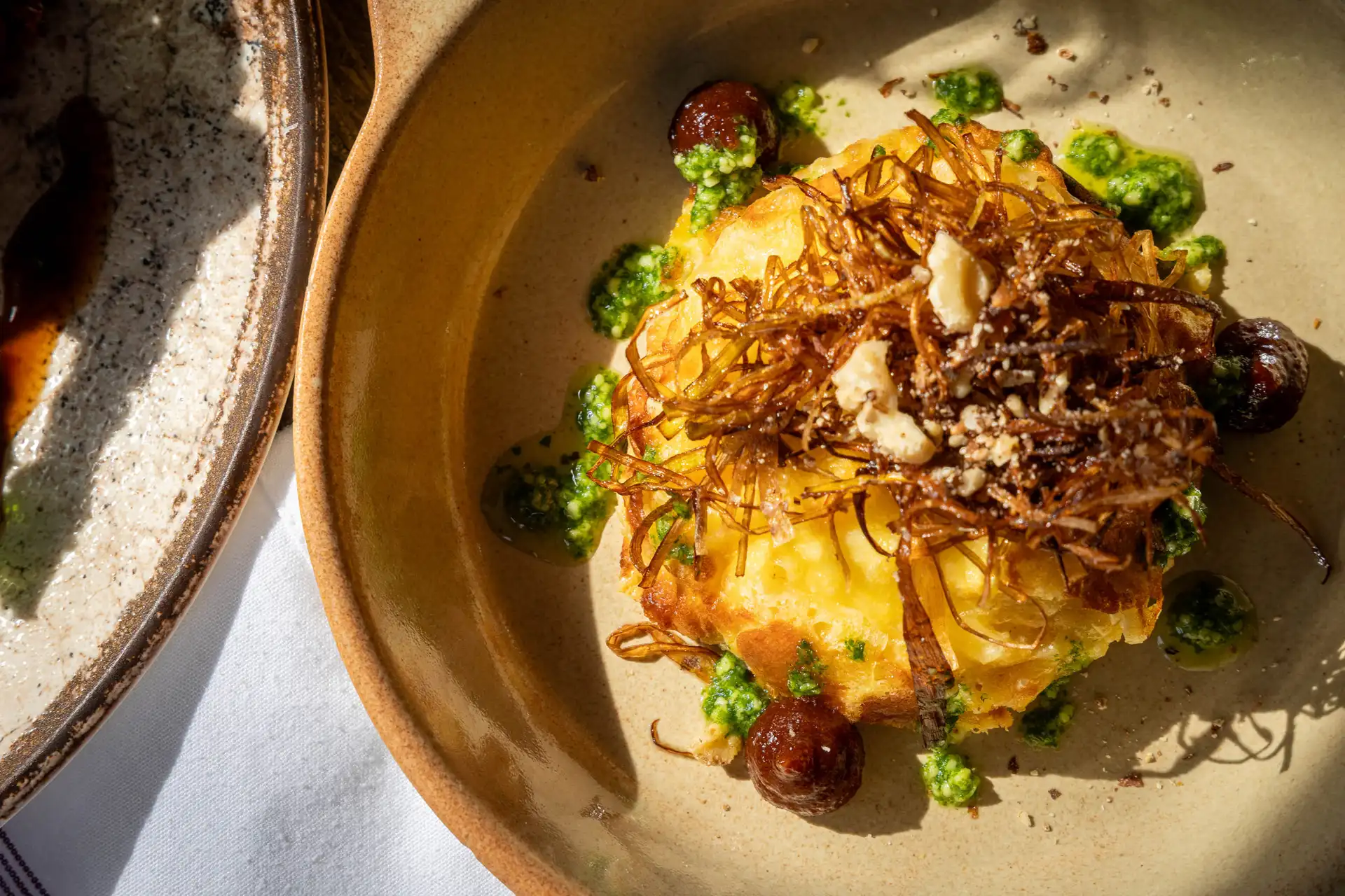 Overhead close-up of Lincolnshire Poacher twice baked soufflé topped with crispy leeks and walnuts, with pickled walnut ketchup