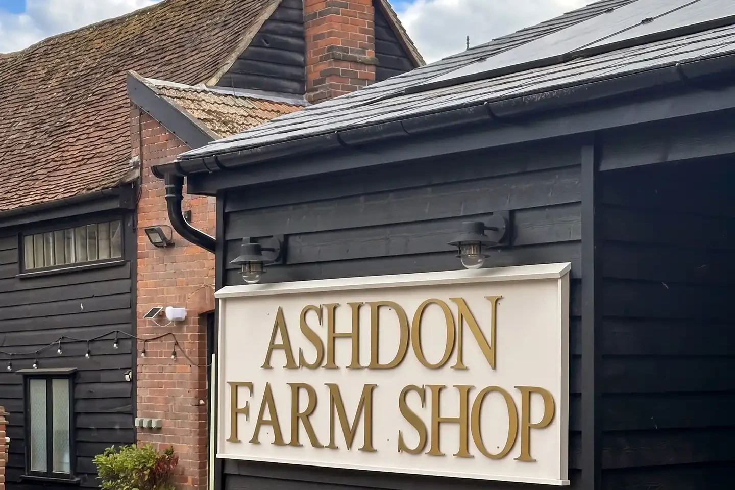Ashdon Farm Shop’s black weatherboarded building with its gold-lettered sign and solar panels, at Crown Hill behind the Rose & Crown